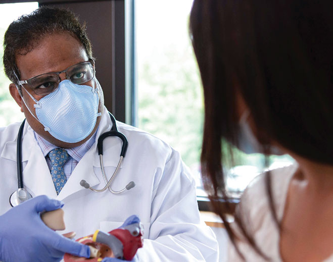 doctor showing a patient a heart model